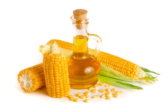 Corn oil in decanter, fresh corn cobs and grains isolated on white background