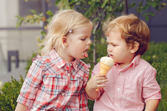 Naklejki Group portrait of two white Caucasian cute adorable funny children toddlers sitting together sharing ice-cream food. Love friendship concept. Best friends forever.