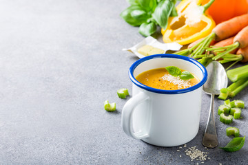 Delicious homemade carrot soup with meat sesame seeds in enamel mug. Healthy food concept with copy space.