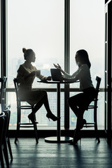 Asian businesswomen in meeting area of office building, looking at tablet computer, filtered image