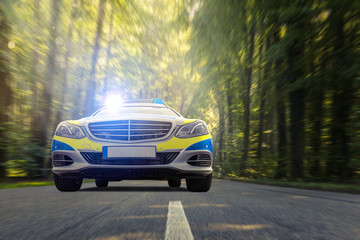 Polizeiauto fährt durch einen Wald © VanHope