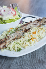 Greek Pork Soulaki Served on a Bed of Rice, Tzatziki Sauce and Salad