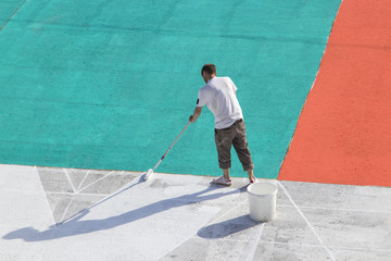 Man at work. Road worker painting asphalt. Worker painting white, red, aquamarine  color on the...