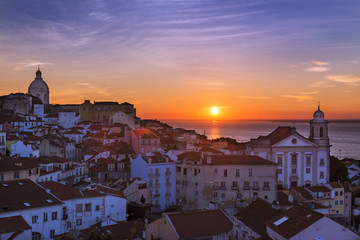 View of the Alfama neighborhood from the Portas do Sol viewpoint at sunrise in Lisbon, Portugal; Concept for travel in Portugal