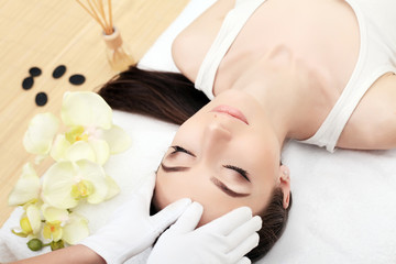 Obraz na płótnie Canvas people, beauty, spa, healthy lifestyle and relaxation concept - close up of beautiful young woman lying with closed eyes and having face or head massage in spa