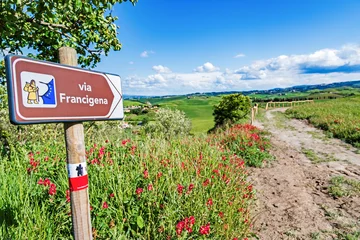 Tuinposter Via Francigena pilgrim path, Tuscany, Italy: road sign at beautiful Tuscany landscape background, spring scenery. Via Francigena is famous pilgrim path and popular travel hiking trail. © Feel good studio