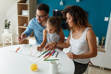 Father and mother teach daughter to draw.They sitting in living room and making fun.