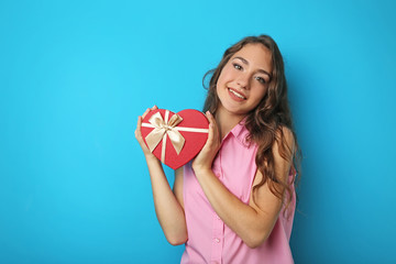 Portrait of young woman with gift box on blue background
