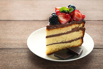 Piece of chocolate cake with berries in plate on wooden table