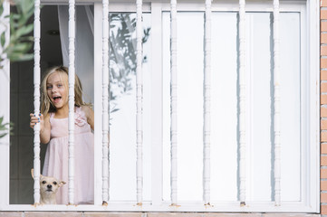 little girl looking in the window with a small dog