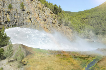 Water flowing, with very pressure, through the spillway of a hydroelectric dam. Small bridge at the...
