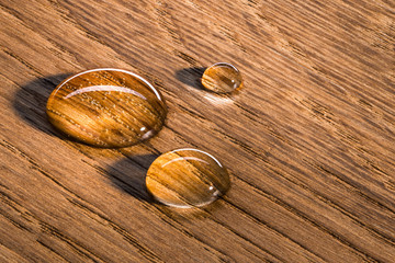Three water beads on finished oak wood