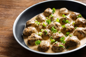 Frying pan with delicious meatballs in sauce on wooden table