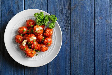 Plate with delicious meatballs on wooden table