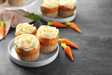 Plate with delicious carrot cupcakes on table
