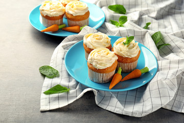 Plate with delicious carrot cupcakes on table
