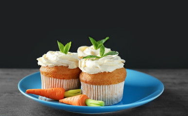 Plate with delicious carrot cupcakes on table