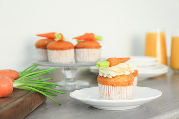 Plate with delicious carrot cupcake on table
