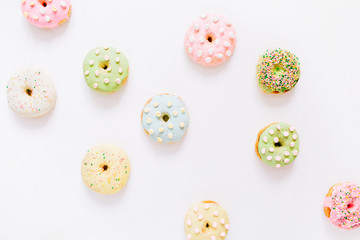 Obraz premium Colorful donuts on white background. Flat lay, top view minimal pattern.