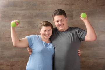 Overweight couple training together on wooden background