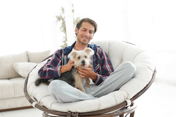 handsome guy with a dog sitting in a large armchair.