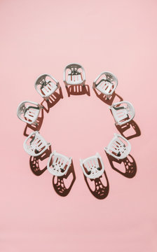 White chairs arranged on pink background in circle.