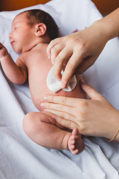 Mother Cleaning the Belly Button of a Newborn Baby
