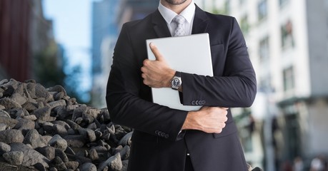 Rubble stones in city with businessman holding laptop