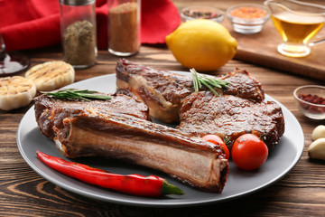 Plate with delicious grilled steaks on wooden table