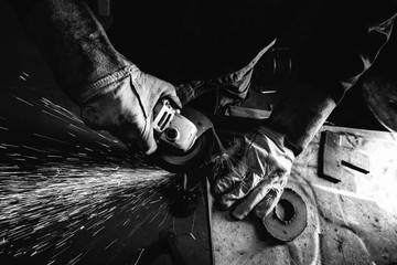 Black and white image of metal worker with angle grinder