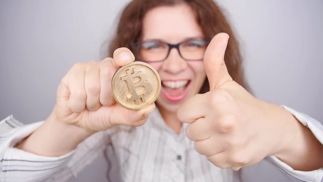 Happy woman holding a Golden Bitcoin