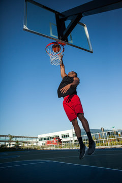 African American man dunking a basketball on an outdoor court