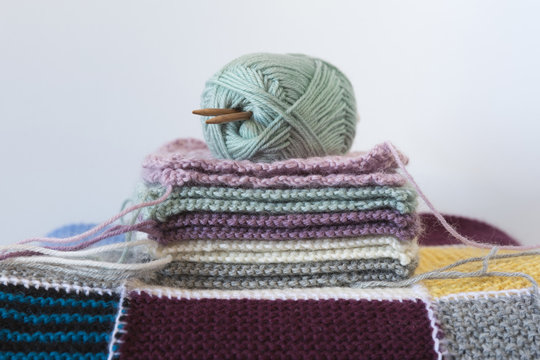Stack of knitted squares with wool and needles