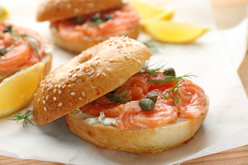 Tasty bagel with salmon on parchment, closeup