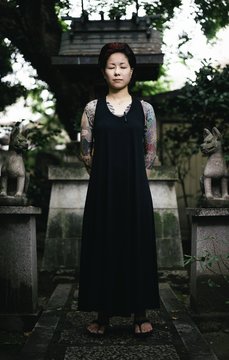 Tattooed Japanese women deeply absorbed in thought while visiting a Shinto Shrine