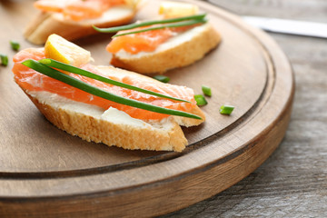 Delicious salmon bruschettas on wooden board, closeup