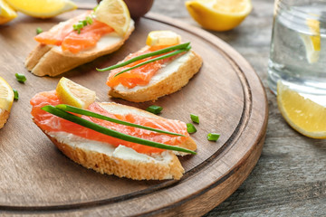 Delicious salmon bruschettas on wooden board, closeup