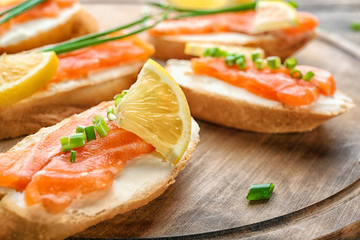 Delicious salmon bruschettas on wooden board, closeup