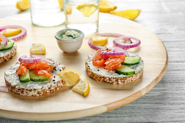 Tasty crispbreads with salmon on wooden board