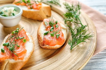 Delicious salmon bruschettas on wooden board, closeup
