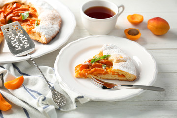 Plate with piece of delicious apricot cake on table