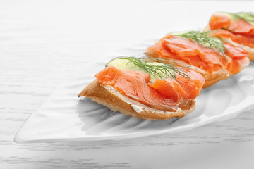 Tasty small sandwiches with salmon and cucumber on plate