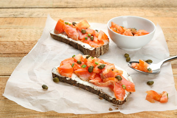 Tasty sandwiches with salmon and capers on paper