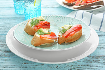 Tasty small sandwiches with salmon and lemon on plate