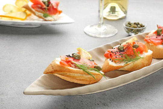 Tasty small sandwiches with salmon and capers on plate