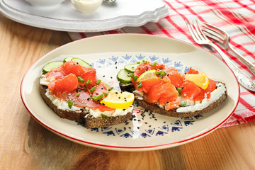 Tasty sandwiches with salmon and lemon on ornate plate