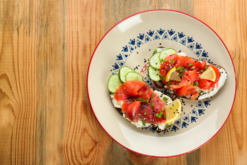 Tasty sandwiches with salmon and lemon on ornate plate