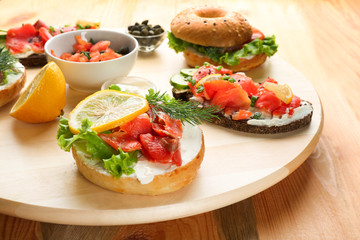 Tasty sandwiches with salmon on wooden board