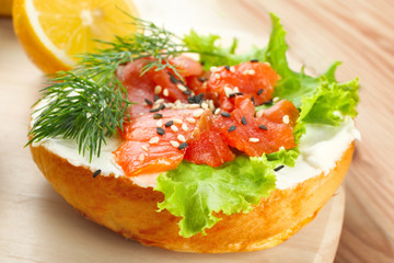 Tasty sandwich with salmon and salad on wooden board, closeup