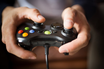 Close up view of joystick in mans hands. Young man holding game controller, palying video games.